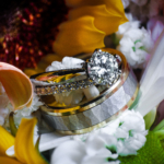 Close up photo of wedding rings sitting on top of flowers.